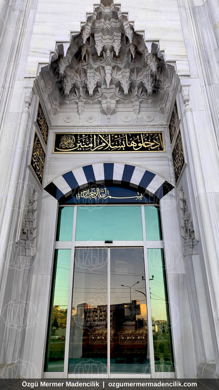 Mukarnaslı taç kapı ve cam girişli beyaz mermer cami kapısı