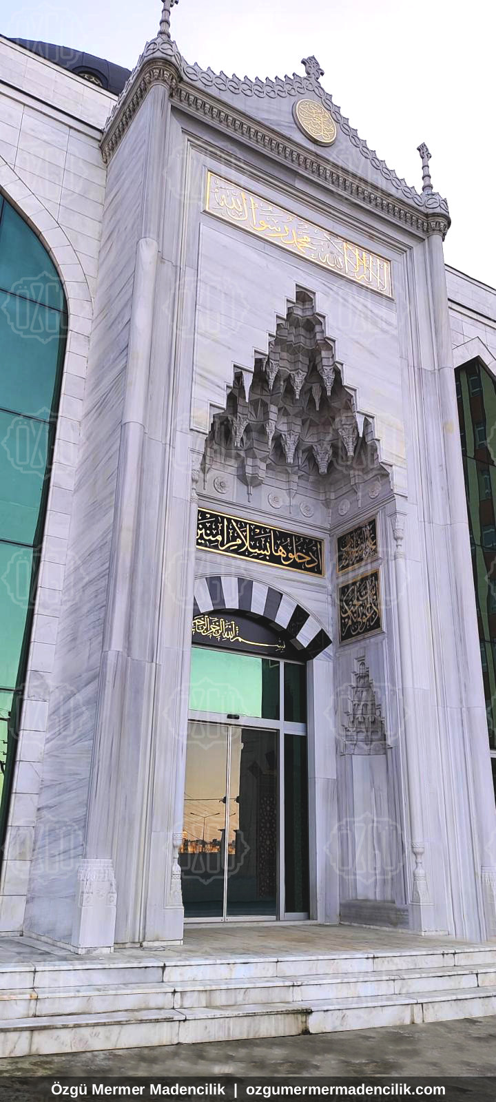 Yüksek beyaz mermer cami taç kapısı ve sivri kemerli giriş